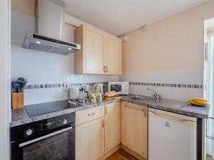 a small kitchen with wooden cabinets and a sink at Bwthyn Hudol - Uk46711 in Pwllheli