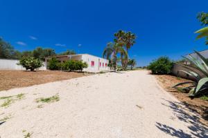 a dirt road with a building and palm trees at Villa Mello in Torre Lapillo
