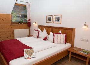 a bedroom with a large bed with red and white pillows at Lechnerhof in Braies