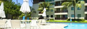 einen Pool mit Stühlen und Sonnenschirmen neben einem Gebäude in der Unterkunft FLAT MARULHOS SUÍTES E RESORT in Porto De Galinhas