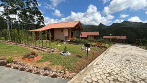 a house with a garden in front of a driveway at Cabanas Vista da Pedra in Grão Pará +12 photos