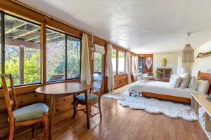 a bedroom with a bed and a table and some windows at Enchanted Waterfall Sanctuary in Mill Valley