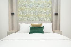 a bedroom with a white bed with a green pillow at The Bantree by Clifton Homes in Accra +38 photos