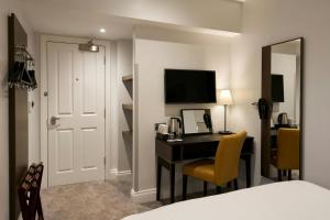 a hotel room with a desk and a television at Four Points Flex by Sheraton London Kensington Olympia in London +6 photos