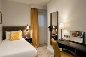 a hotel room with a bed and a desk and a desk at Four Points Flex by Sheraton London Kensington Olympia in London