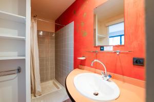 a bathroom with a sink and a red wall at Logis Hôtel Le Keréden in Locarn +15 photos