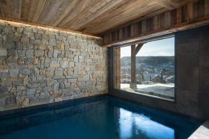 a swimming pool with a stone wall and a window at Sorelle Chalet, spa, indoor pool, lake view in Gérardmer