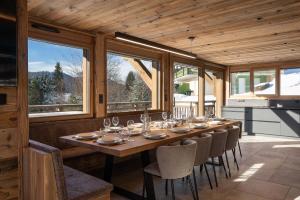 a long wooden table in a room with windows at Sorelle Chalet, spa, indoor pool, lake view in Gérardmer