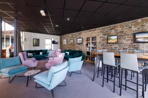 a restaurant with blue and pink chairs and a brick wall at Logis Hôtel Le Keréden in Locarn