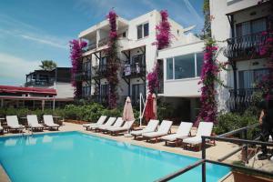 a hotel with a swimming pool and lounge chairs at Hotel Gumbet in Bodrum City