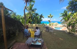 a group of people sitting at a table by a pool at Le Rocher De Machabee in Mahe