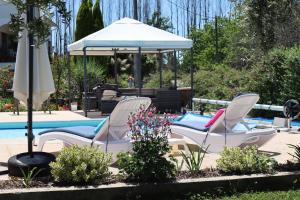 zwei Stühle und ein Sonnenschirm neben einem Pool in der Unterkunft Luxury Private apartment FREE Play Park inc QUID BIKES PRIVATE Heated swimming pool in Sinde