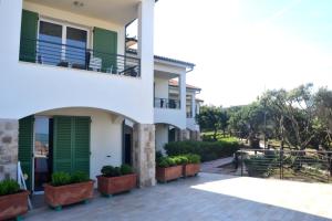 a white house with green shutters and potted plants at Etruriamare in San Vincenzo