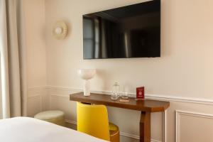 a room with a table with yellow chairs and a mirror at Almarine Eiffel Hotel & Spa by Malone in Paris