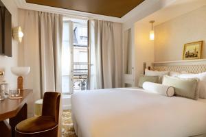 a hotel room with a bed and a desk and a window at Almarine Eiffel Hotel & Spa by Malone in Paris +45 photos