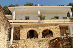 an old stone house with a stone wall at Rogdia Mountain View Apartment in Rogdhiá