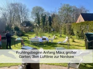 Ein Mann steht in einem Garten mit einem Tisch und Stühlen. in der Unterkunft FeWo "Ebbe" im historischen Denkmal, ruhig & modern mit Stil, Kunst und großem Garten, hochwertiger Ausstattung & zentraler Lage in Esens- 3km zur Nordsee, alles fußläufig erreichbar - ideal für Paare oder kleine Familien in Esens