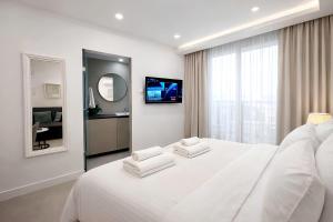 a white bedroom with a large bed with two white towels at White Arches Studio Suite by TrulyCyprus in Limassol