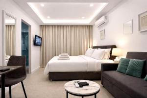a hotel room with a bed and a couch at White Arches Studio Suite by TrulyCyprus in Limassol