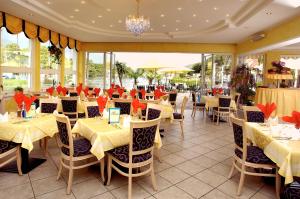 a restaurant with yellow tables and chairs and windows at Seehotel Steiner in Seeboden