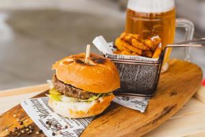 a hamburger and french fries on a wooden board withbeer at Glamping Terme Tuhelj in Tuheljske Toplice