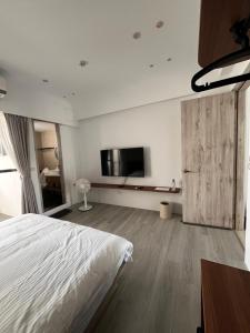 a bedroom with a bed and a flat screen tv at Zao Orange Homestay in Taitung City