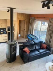 a living room with a black couch and a stove at De Notelaar in Alveringem