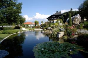 a pond in a garden with a house in the background at Seehotel Steiner in Seeboden