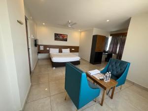 a hotel room with a bed and a table and chairs at Hotel Park Varaahi in Tirupati
