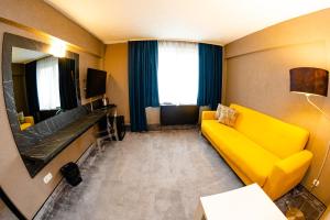 a living room with a yellow couch and a television at Hotel Ciao in Târgu-Mureş