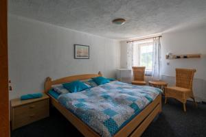 a bedroom with a bed and two chairs and a window at Penzion Tomy Pihlov in Horní Planá