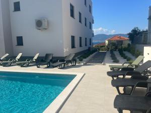 a swimming pool with lounge chairs next to a building at Tina's Tiny Beach House in Slatine