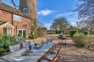 a wooden table and chairs in front of a building at Finest Retreats - The Old Windmill in Hindolveston
