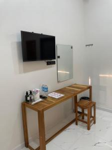 a table with a mirror and a television on a wall at NIRAN Hotel & Residence in Ban Talai