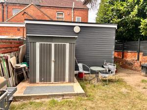 a black shed with a table and chairs in a yard at ChaRloHub 01 in Coventry