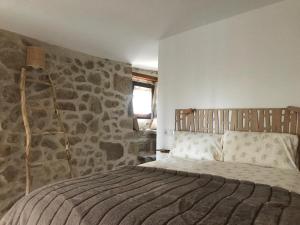 ein Schlafzimmer mit einem Bett vor einer Steinwand in der Unterkunft Casa Media Lúa in Allariz