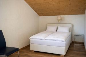a white bed in a room with a lamp and a chair at Ferienwohnung Kramerblick Marienplatz in Garmisch-Partenkirchen