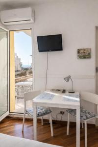 a room with a table and chairs and a tv on the wall at Le VELE in Lido di Ostia