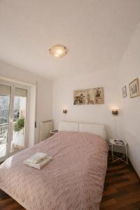 a white bedroom with a large bed and a window at Le VELE in Lido di Ostia
