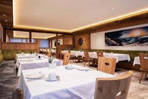 a restaurant with white tables and chairs and a large screen at Vital Hotel Post in Dienten am Hochkönig