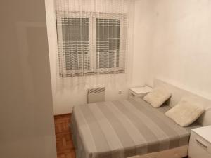 a small bedroom with a bed and a window at Apartman Vuk in Ćuprija