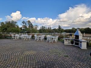 a patio with white tables and chairs and a grill at Galgenberghof Müncheberg in Müncheberg