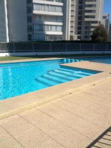 una piscina azul con edificios altos en el fondo en Coraceros Apartment, en Viña del Mar