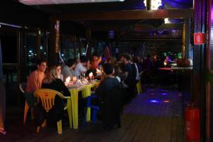 a group of people sitting at a table in a restaurant at Aquario Pousada Hostel - Night Club in Abraão