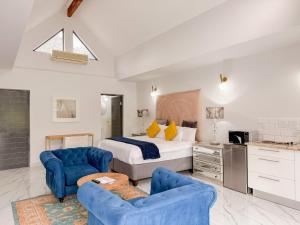 a bedroom with a bed and two blue chairs at Amoris Guesthouse I - Randburg in Johannesburg