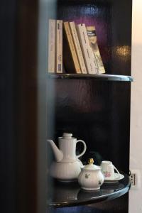 a shelf with a tea pot and cups and books at Villa 18 Hostel in Tirana