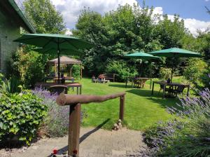 a garden with tables and chairs and umbrellas at Gästehaus Hoxel in Hoxel