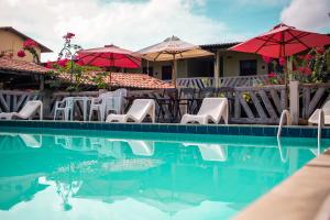 a pool with tables and chairs and umbrellas at Hotel Pousada Dos Ventos in Parnaíba