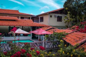 a house with an umbrella and a swimming pool at Hotel Pousada Dos Ventos in Parnaíba