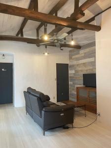 a living room with a black couch and a tv at HANARE onomichi in Onomichi